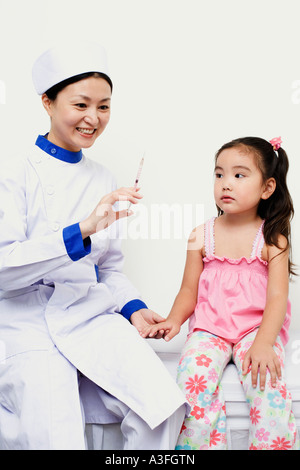 Female nurse holding a girl and a syringe Stock Photo