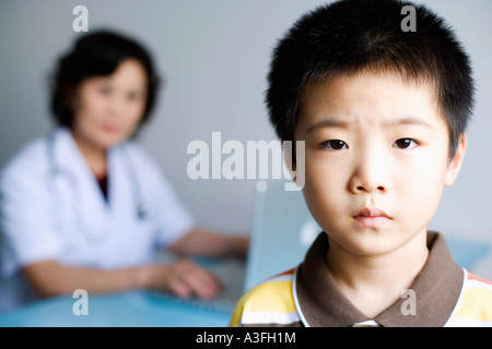 Portrait of a boy with a female doctor working on a laptop in the background Stock Photo