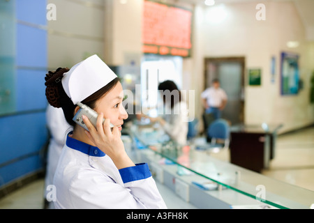 Side profile of a female nurse talking on the telephone Stock Photo
