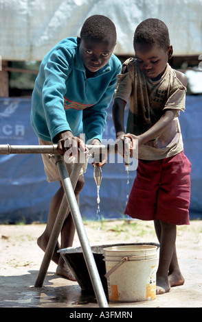 Angola, boys fetching water at a dry water pipe in a refugee camp in Luau, border to Zambia Stock Photo