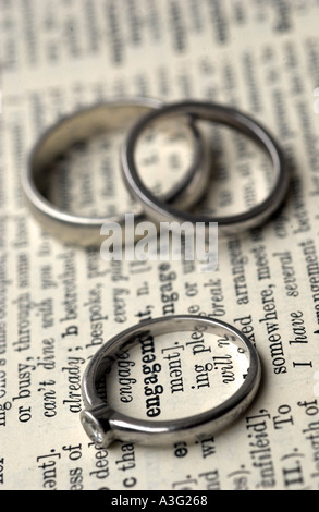 Engagement and wedding rings on a dictionary showing the word engage Stock Photo