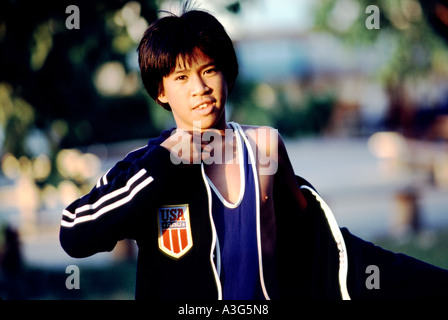 Determined competitive teenaged boy puts on his black windbreaker before he leaves for an important wrestling match Stock Photo