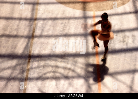 Dramatic overhead silhouette of a young woman practicing  for a figure skating competition in an in door ice rink. Stock Photo