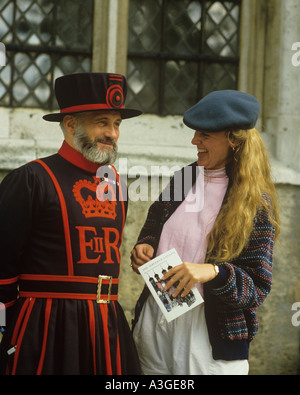 attractive smiling female tourist poses for picture with beefeater Yeoman guard at The Tower of London Stock Photo