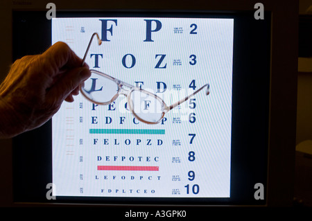 hand holding glasses in front of eye chart Stock Photo