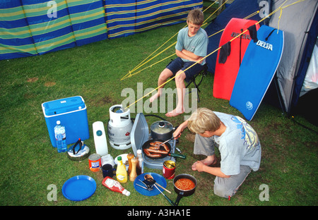 Two boys cooking on a camping holiday Polzeath North Cornwall coast England Britain UK Stock Photo