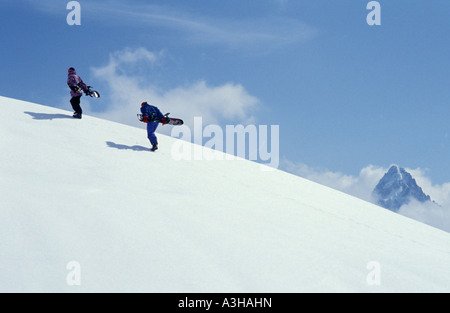 two snowboarders walking up the snowy slope in the French alps Stock Photo