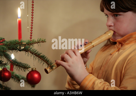 young girl playing the recorder in front of a Christmas Tree Stock Photo