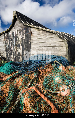 Upturned fishing boat used as a shed with fishing tackle and nets outside on Holy Island, Lindisfarne Stock Photo