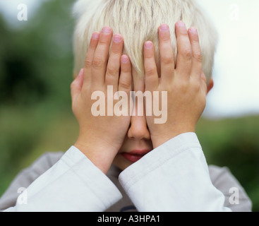 Young boy with hands over his eyes Stock Photo