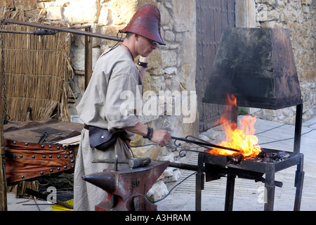 Blacksmith in medieval costume forging steel with fire in village of Peratallada in Spain Stock Photo