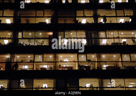 Illuminated office building at night, with several windows showing people working inside in Bucharest Romania Stock Photo
