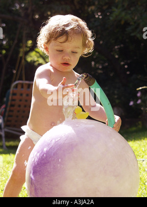 little girl with garden hose with ball Stock Photo
