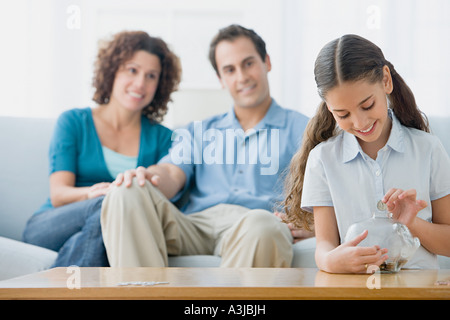 Girl putting coins in a piggy bank Stock Photo