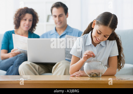 Girl putting coins in a piggy bank Stock Photo