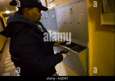 A United States Postal Service delivers mail to an apartment building mail boxes in Harlem New York City USA January 2006 Stock Photo
