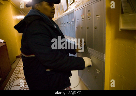 A United States Postal Service delivers mail to an apartment building mail boxes in Harlem New York City USA January 2006 Stock Photo