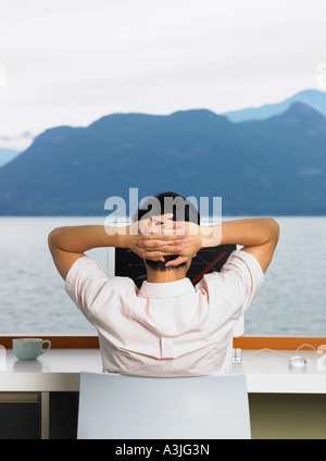 Man Using Computer in Front of Window with Ocean View
