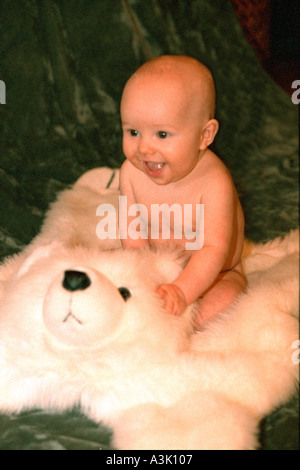 Baby boy smiling happily sitting on stuffed polar bear rug. St Paul Minnesota USA Stock Photo