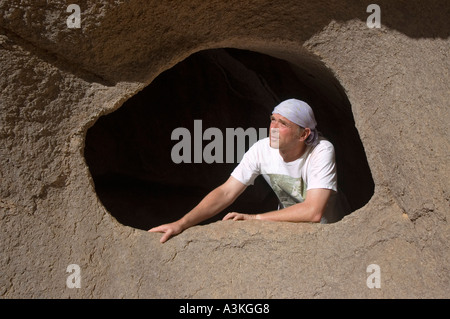 Man looking through a hole in the rock, Jebel Uweinat, Jabal al Awaynat, Libya Stock Photo