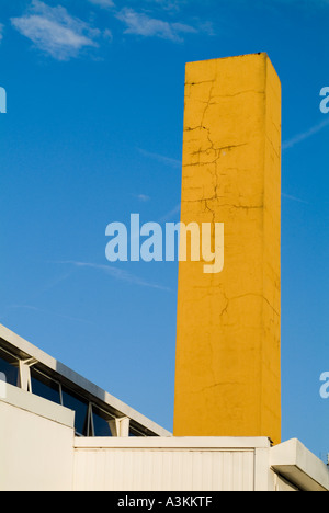 Tall brick chimney painted yellow. Stock Photo