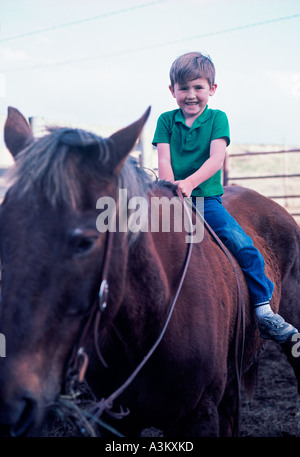 Little boy riding horse in corral Stock Photo