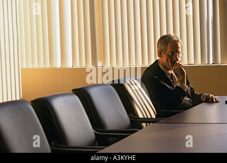 Pensive executive sitting alone in boardroom Stock Photo