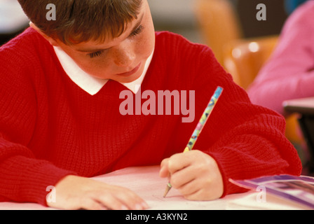 Caucasian male student writing in elementary school class Stock Photo