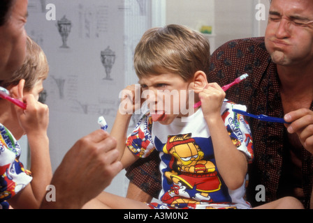 Caucausian father and son make faces in mirror while brushing teeth Stock Photo