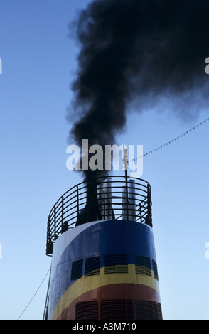 Pollution close up of belching black smoke & soot emissions from ship funnel into air atmosphere damaging the environment & contributes human disease Stock Photo