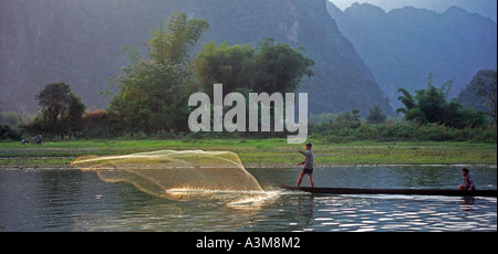 Men in canoes cast nets to catch fish in late afternoon, on the Nam Xong River, Vang Vieng, Laos. DN32 Stock Photo