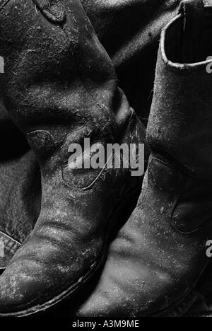 Cowboy boots covered in dried hay and grass and worn out leather Canada Stock Photo