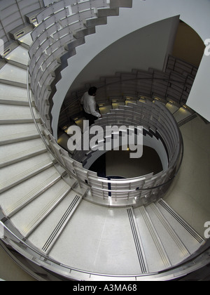 View from above of man walking up circular staircase in hospital Stock Photo