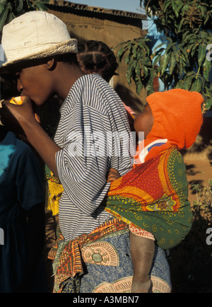 A neighborhood in Maputo Mozambique with women walking and carrying babies over their backs wrapped in shawls Stock Photo