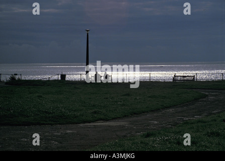 People sitting on bench on Gunhill Southwold Suffolk England Stock Photo