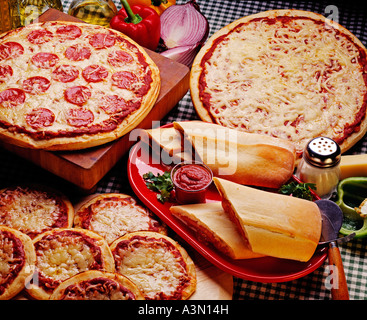 Italian pizza pie Stromboli mini pizzas cheese pepperoni tomato tomatoes sauce onions pepper garlic salt wood cutting board Stock Photo