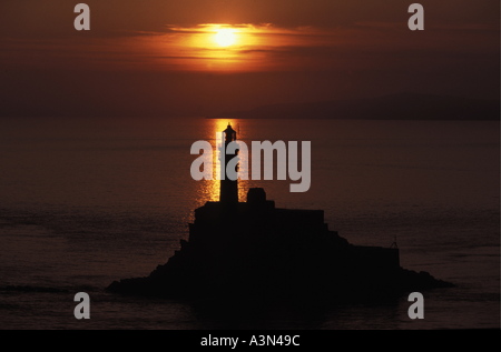 Fastnet rock and lighthouse at sunset on calm sea Stock Photo