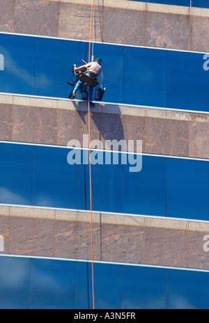 Window washer skyscraper.  Workman suspended on the exterior of a modern skyscraper in Austin Texas. High rise building maintenance Stock Photo