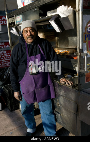 Middle eastern man selling hot dogs by his cart on 6th Avenue on New York USA january 2006 Stock Photo