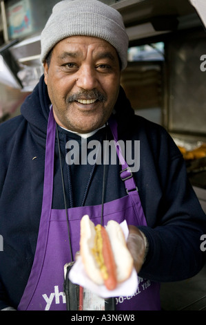 Middle eastern man selling hot dogs by his cart on 6th Avenue on New York USA january 2006 Stock Photo