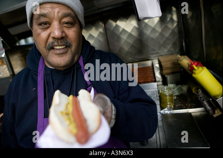 Middle eastern man selling hot dogs by his cart on 6th Avenue on New York USA january 2006 Stock Photo