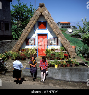 THREE WOMEN IN FRONT OF A  PALHEIRO  TRADITIONAL THATCHED HOUSE  SANTANA  VILLAGE  MADEIRA  ISLAND PORTUGAL EUROPE Stock Photo