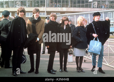 BEATLES leaving Heathrow to film HELP in 1965. From l: George, Paul, Ringo, Maureen, Cynthia, John Stock Photo