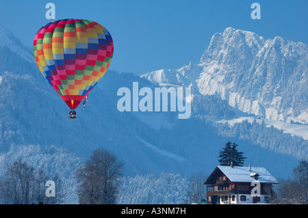A balloon flying through the Swiss Alps at Chateau d'Oex, passing over a typical Swiss chalet