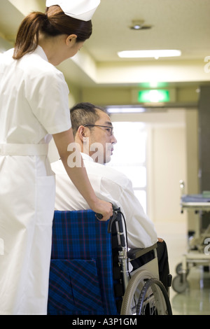 Female nurse pushing a patient in wheelchair Stock Photo