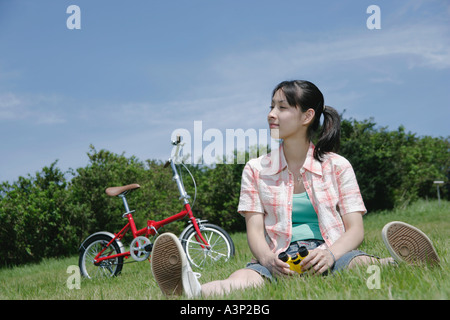 Young woman sitting on grass field Stock Photo