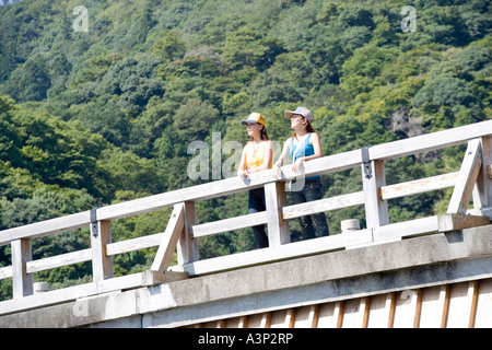 Two young women standing on togetsu bridge in Arashiyama, Kyoto, Japan Stock Photo