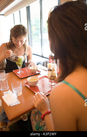 Two young women eating ice cream in coffee shop Stock Photo