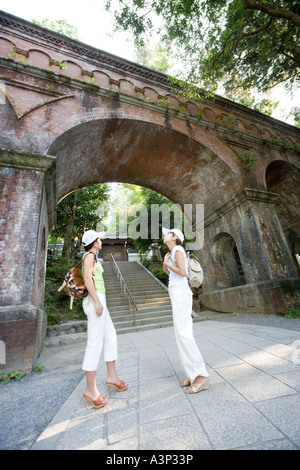 Two young women standing under bridge Stock Photo