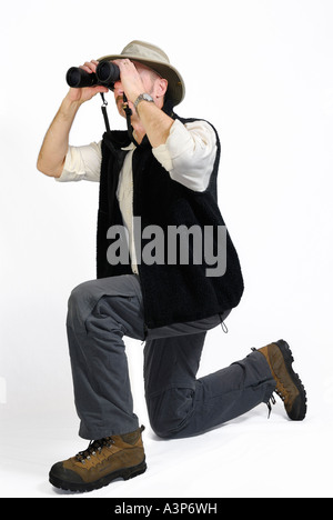 Kneeling man looking through binoculars on white background Stock Photo